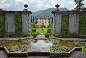 Giardino all'italiana di una villa da sogno, con piante curate e fiori colorati in un ambiente sereno.