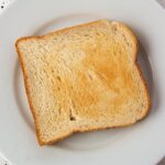 Fette biscottate su un tavolo con un cartello che indica marche da evitare per la salute del cuore.